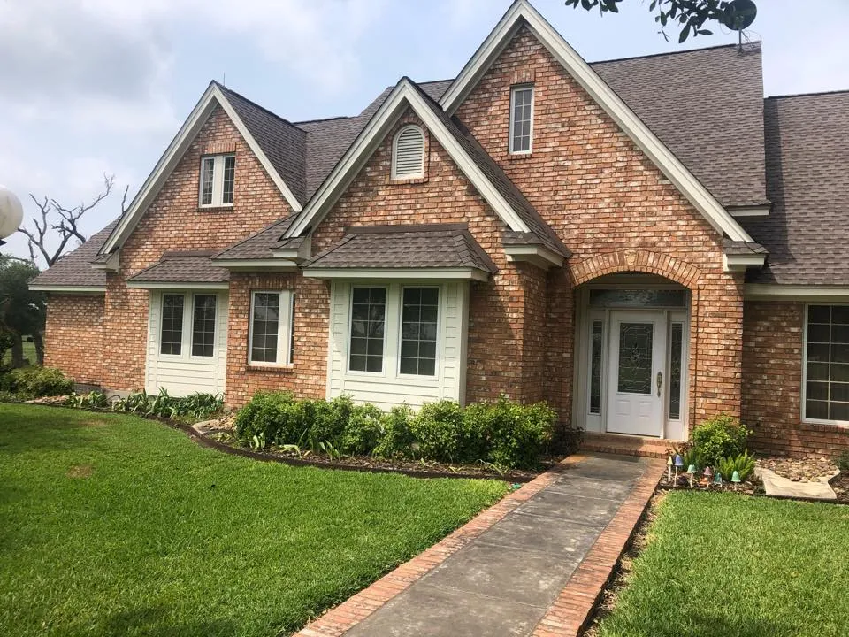 Brick house with a shingle roof and several front gables.