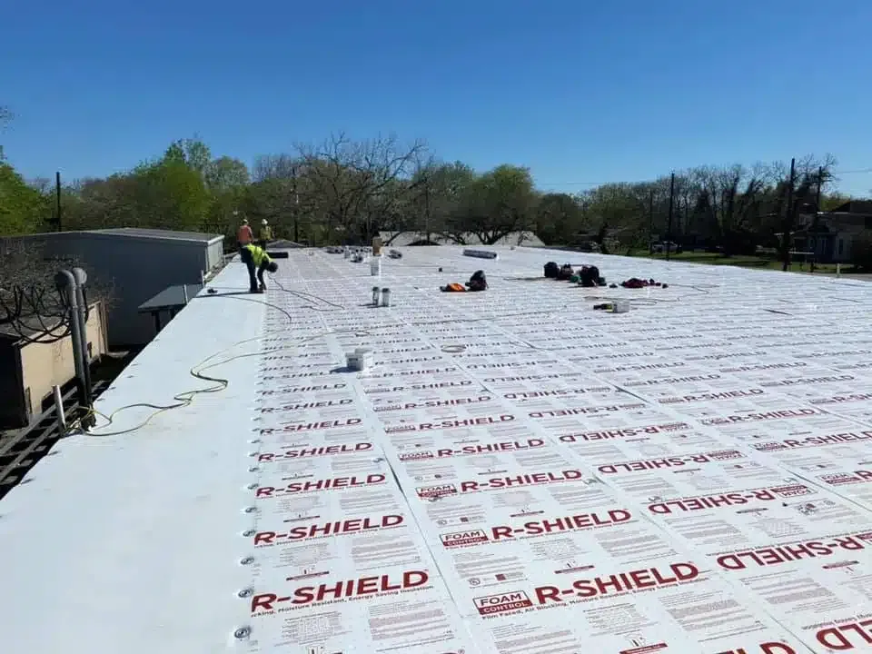 Insulation being installed beneath a roof.