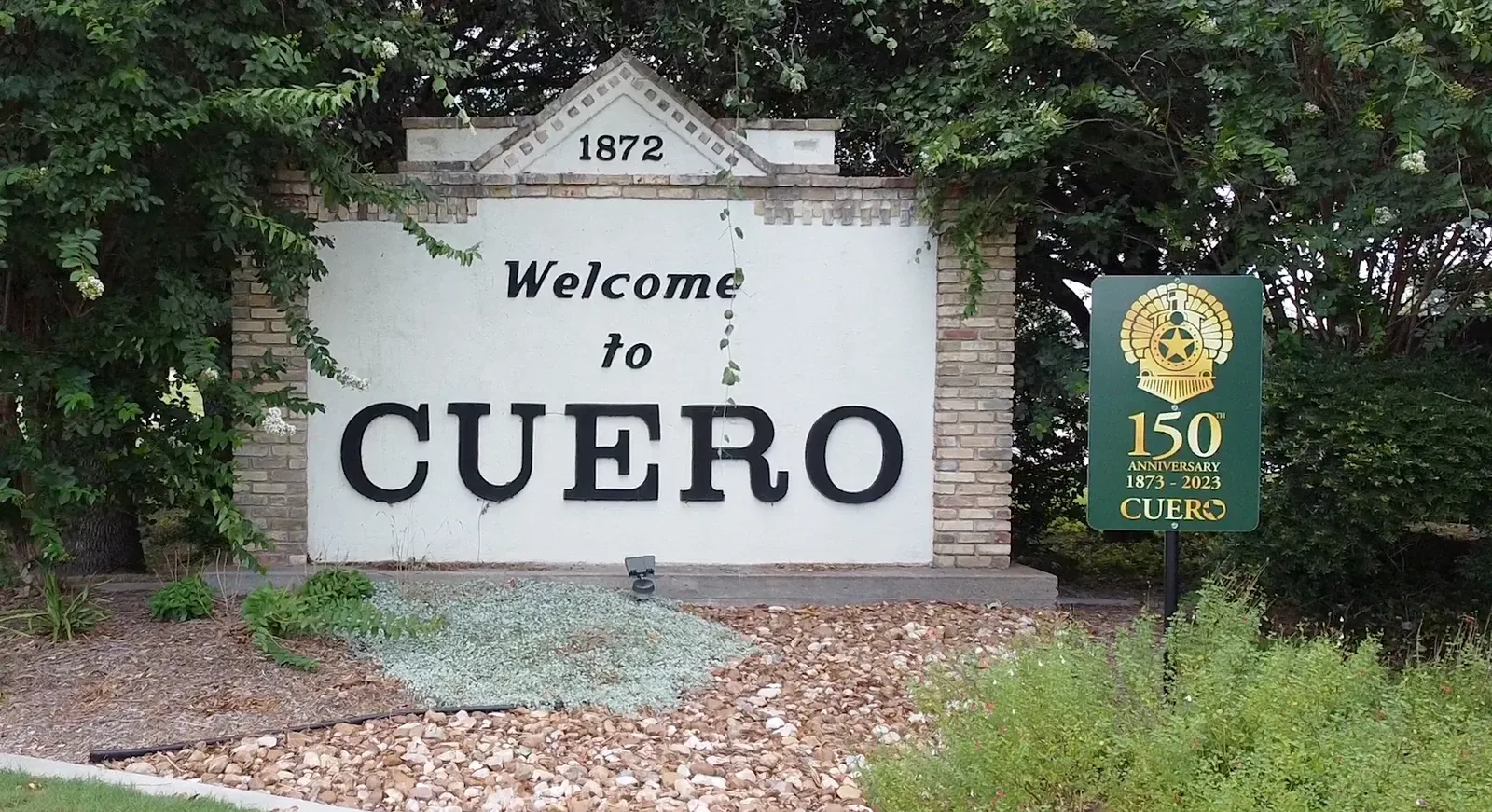The welcome sign in Cuero, Texas, surrounded by trees.