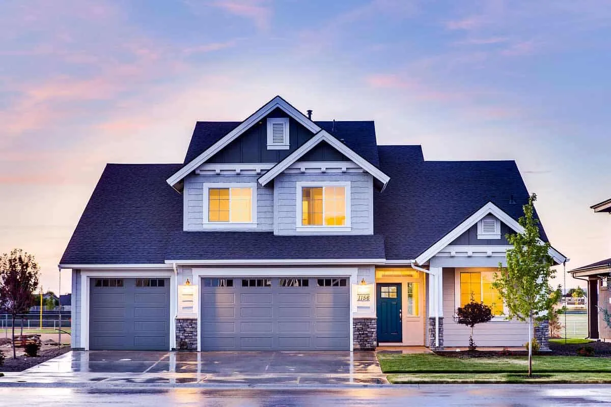 Two-story home with a blue shingle roof at dusk.