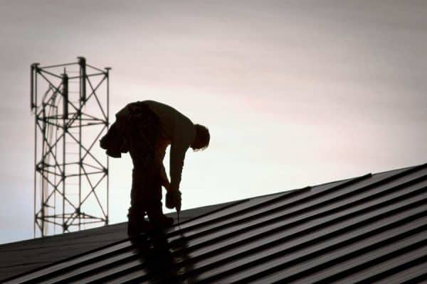 Silhouette of roofing contractor on roof