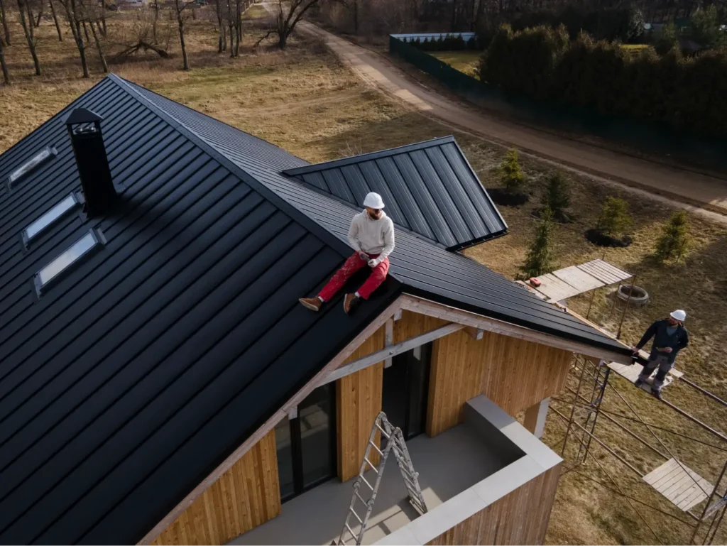 A roofer sits perched atop the house after he finished installing the new roof.