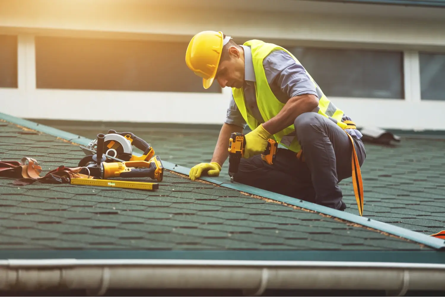 A man in a hard hat works to roof a house. Repairing or replacing an old roof can be vitual to the upkeep of your home.