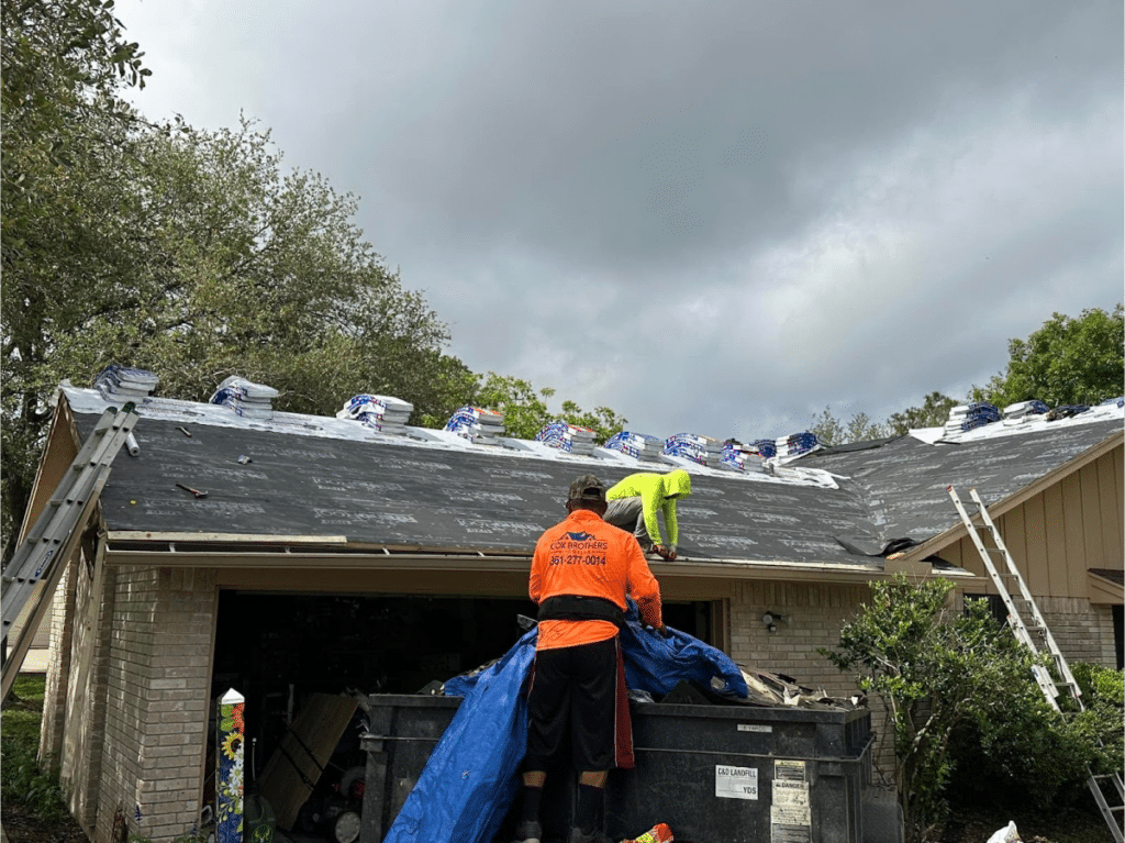 Roofers preparing a roof with underlayment before shingle installation.