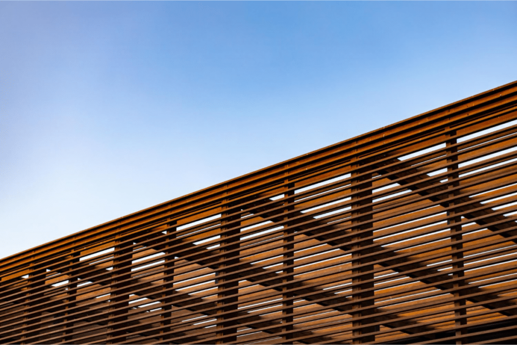 Close-up of a wooden slat facade with clear blue sky behind.